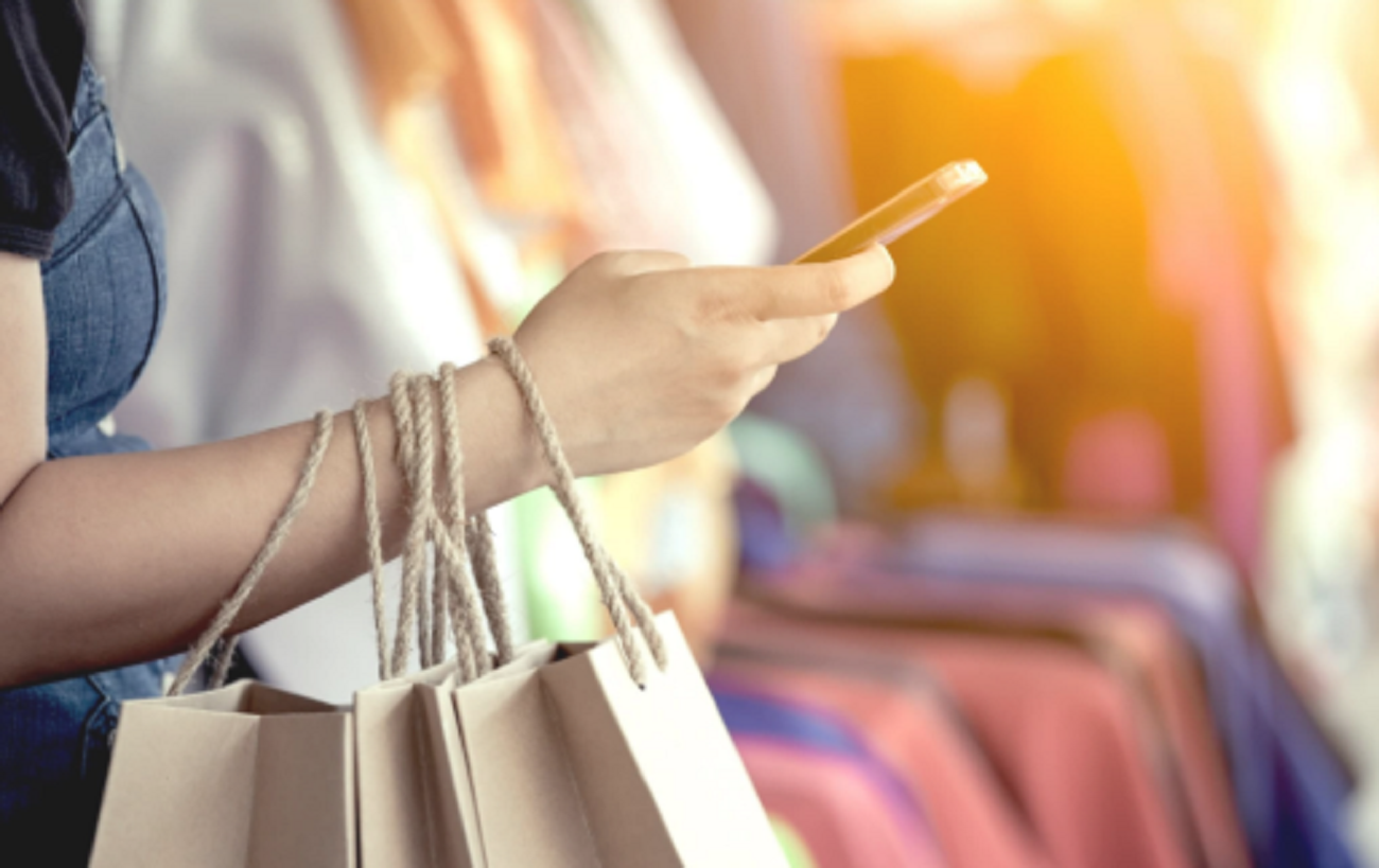 Lady carrying shopping bags in a store and on her mobile device